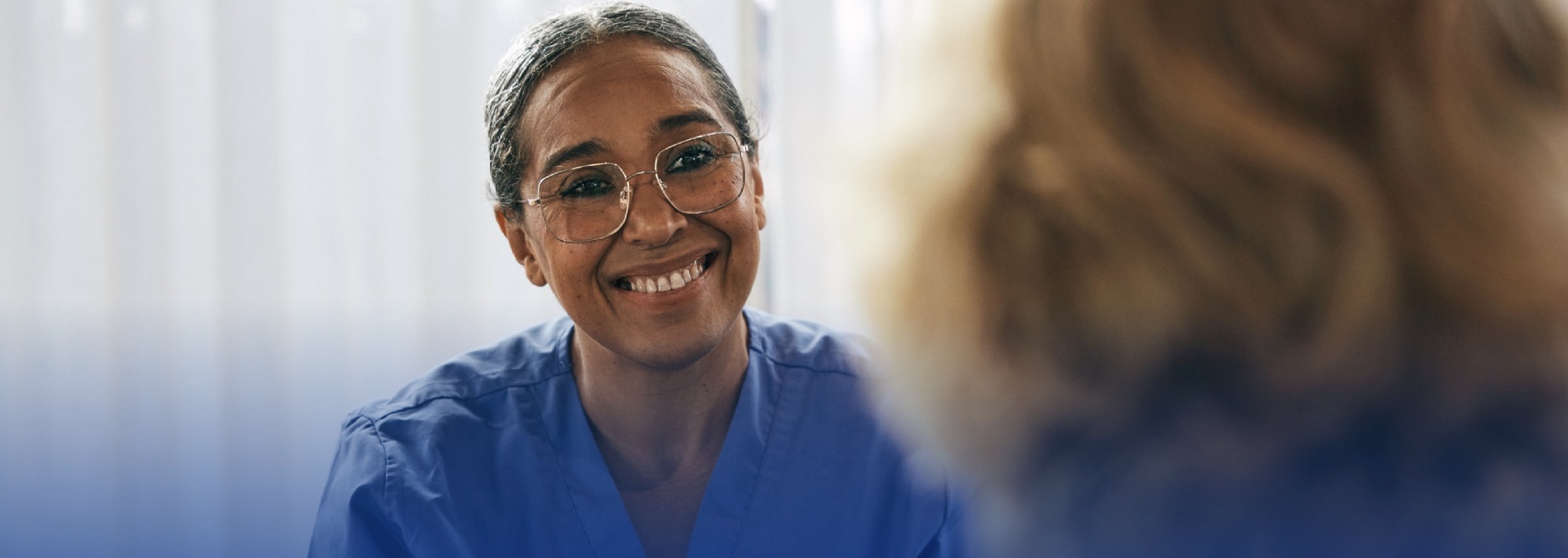 Healthcare professional in scrubs speaking with a patient